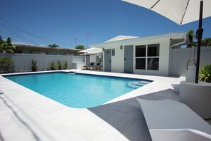 A swimming pool with a white deck, a covered seating area, and a house with a white exterior. - Modern 2BR/2BA • Pool • Parking • Near Beach / Victoria Park / Las Olas (Fort Lauderdale)