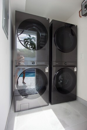 A stacked washer and dryer unit with a view of a swimming pool through the door. - Modern 2BR/2BA • Pool • Parking • Near Beach / Victoria Park / Las Olas (Fort Lauderdale)