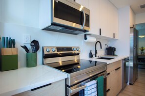 Una cocina moderna con electrodomésticos de acero inoxidable, microondas, horno y lavavajillas integrado.
