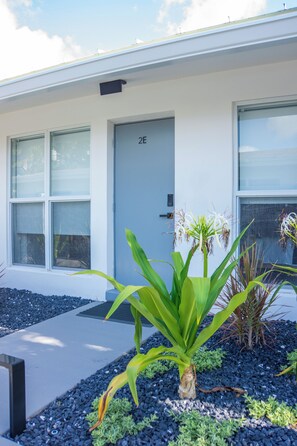 A modern building with a flat facade, a door labeled '2E', and a window with a security keypad. - Modern 2BR/2BA • Pool • Parking • Near Beach / Victoria Park / Las Olas (Fort Lauderdale)