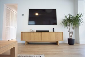 Una sala de estar moderna con un mueble de madera, un televisor de pantalla plana montado en la pared y una planta en maceta.