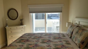 Une chambre à coucher avec un lit, une commode, un miroir et une vue sur l’extérieur.