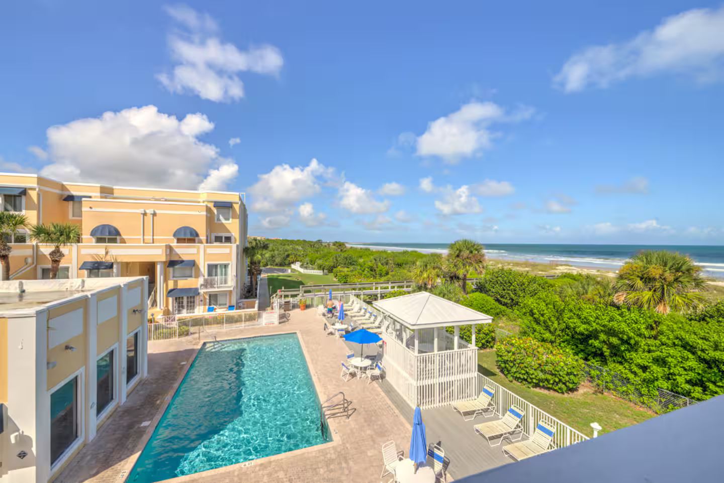 A hotel with a pool, lounge chairs, and a view of the ocean.