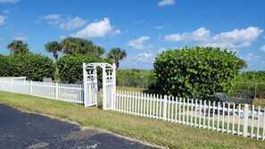 A gated area with a white picket fence, a pergola, and a well-maintained lawn. - Amazing 2 /2 Beachside Get Away w/Nice Ocean View! (Cape Canaveral)