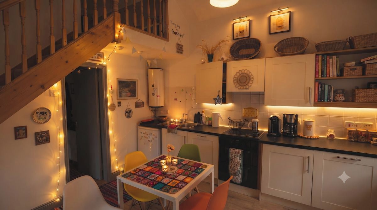 A cozy kitchen with a dining area, wooden staircase, and various kitchen appliances.