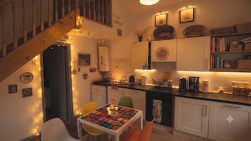 A cozy kitchen with a dining area, wooden staircase, and various kitchen appliances.