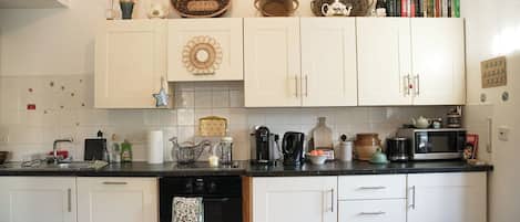 A kitchen with white cabinets, a black countertop, and various kitchen appliances.