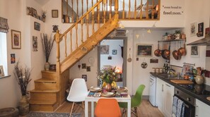 A cozy kitchen with wooden stairs, a dining table with chairs, and various kitchen utensils. - Farm Studio, Sleeps 5, Digital Disconnect (Ferns)