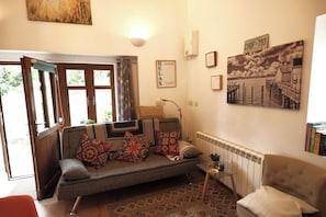 A cozy living room with a sofa, a small side table, and a radiator.