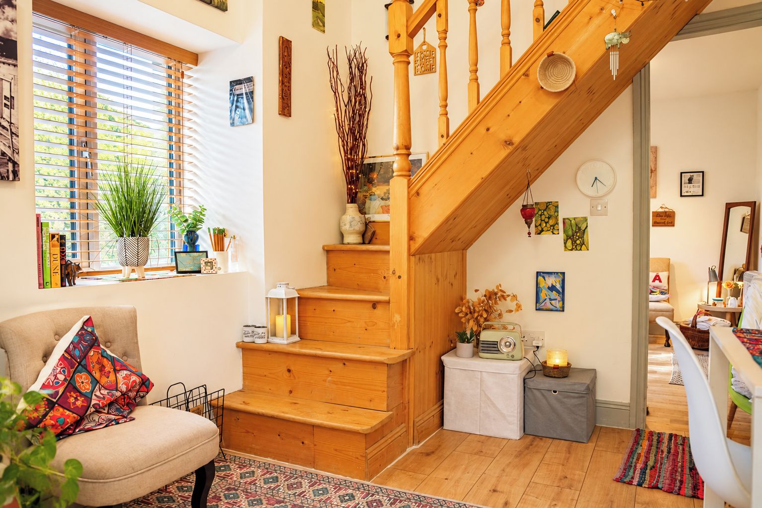Un salon chaleureux avec un escalier en bois, un canapé confortable et une petite table sur laquelle se trouve une radio.