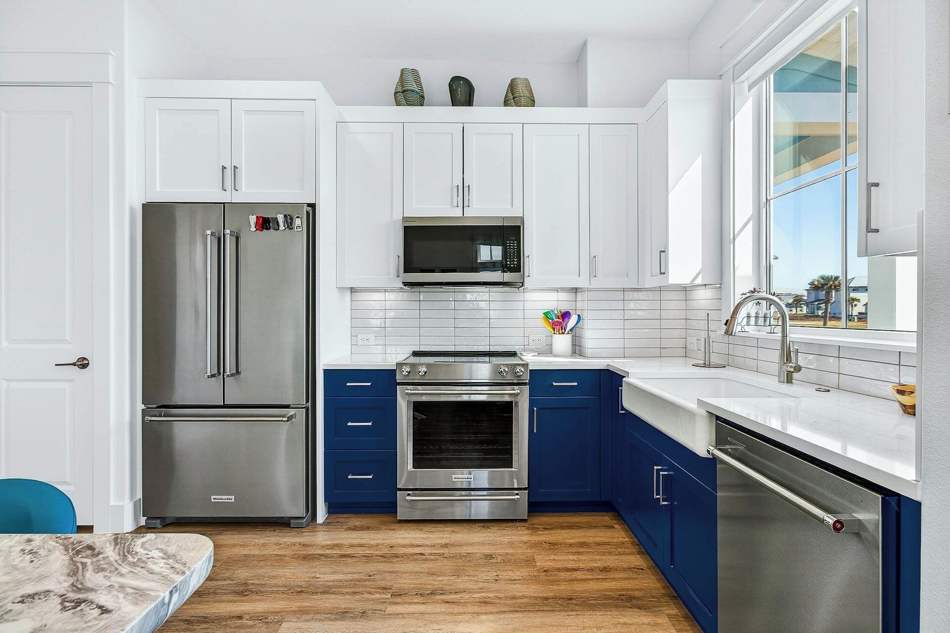A modern kitchen with white cabinets, stainless steel appliances, and a blue accent wall.