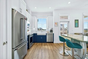 Una cocina moderna con electrodomésticos de acero inoxidable, una isla azul y vistas al exterior.