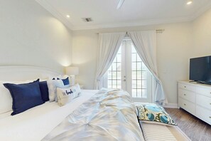 A bedroom with a bed, a television, and a window with curtains. - Resort Views | Private Patio | Beach Escape (Port Aransas)