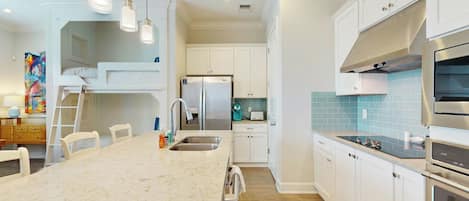 A modern kitchen with a central island, stainless steel appliances, and white cabinetry.