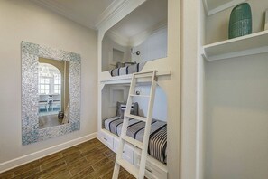 Ein Zimmer mit Etagenbetten, einem Zier-Spiegel und Holzboden.