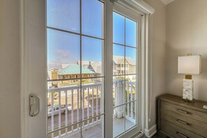Ein Zimmer mit einem großen Fenster, einem hölzernen Schminktisch und einer Lampe.