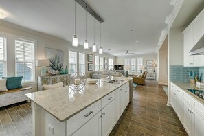 A spacious kitchen with a large island, pendant lighting, and a view to the living area. - Palmilla Beach | Steps to Beach | Resort Amenities (Port Aransas)