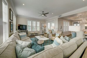 Ein geräumiges Wohnzimmer mit einer großen Couch, einem Esstisch und einem Fernseher.