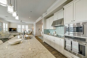 Een moderne keuken met witte kasten, roestvrijstalen apparatuur en een marmeren aanrecht.
