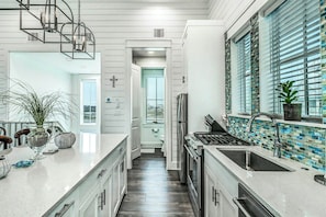 A modern kitchen with a central island, stainless steel appliances, and a view to the outside. - Ca-SEA-ta | Steps to Beach | Resort Amenities (Port Aransas)