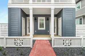 A two-story house with a front porch, white railings, and a brick pathway leading to the entrance. - Ca-SEA-ta | Steps to Beach | Resort Amenities (Port Aransas)
