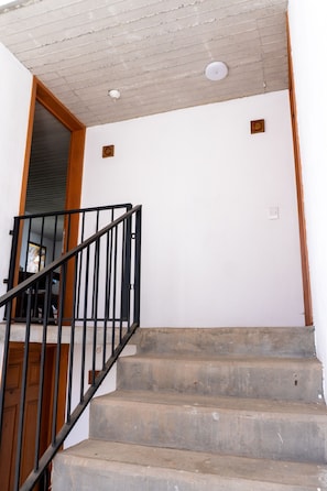 A staircase with a wooden handrail and a white wall.