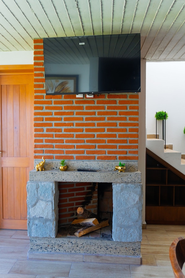 A fireplace with a flat-screen TV mounted above it, set against a brick wall.