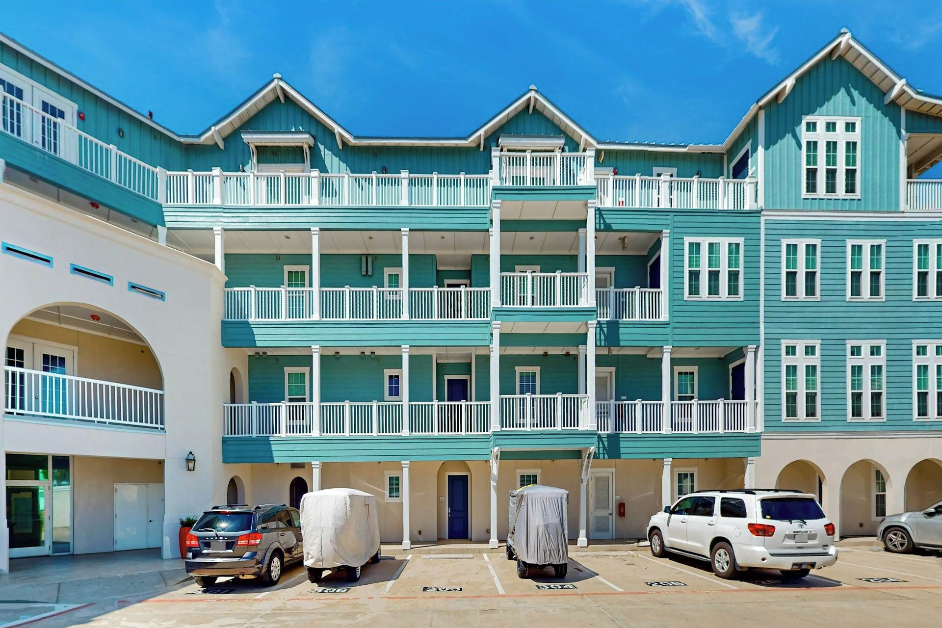 Un immeuble à plusieurs étages doté de balcons et d’un espace de stationnement.