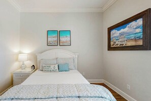 Una camera da letto con un letto, un comodino, una lampada, due quadri incorniciati e un dipinto.