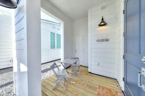 Ein Zimmer mit Holzboden, einem Tisch mit zwei Stühlen, einer Tür mit einer Lampe und einem Fenster mit grün getöntem Glas.