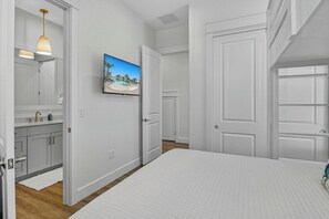 Quarto com cama, banheiro com pia e espelho, e corredor com portas.