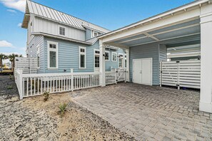 A two-story house with a garage, a fenced patio, and a paved driveway. - Starfish Cove | Steps to Beach | Resort Amenities (Port Aransas)