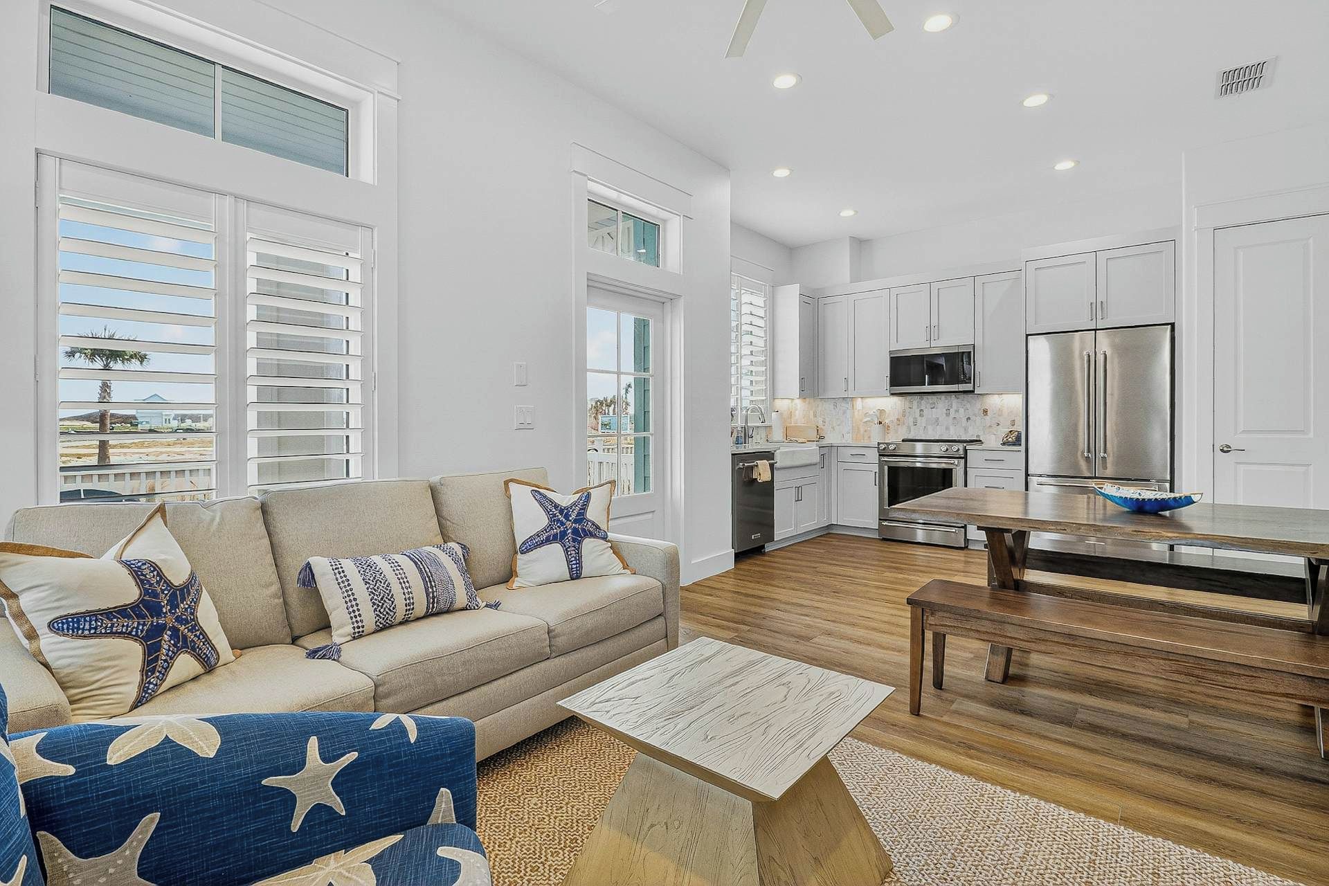 A modern kitchen with white cabinets, stainless steel appliances, and a wooden dining table.