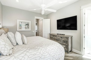A bedroom with a bed, a ceiling fan, a television, and a fireplace. - Top Of The Shoreline | Golf Views | Steps to Beach (Port Aransas)