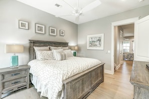 A bedroom with a large bed, a ceiling fan, and framed artwork on the wall. - Top Of The Shoreline | Golf Views | Steps to Beach (Port Aransas)