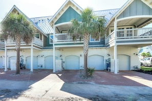 A multi-story building with a symmetrical facade, multiple balconies, and a series of garage doors. - Top Of The Shoreline | Golf Views | Steps to Beach (Port Aransas)