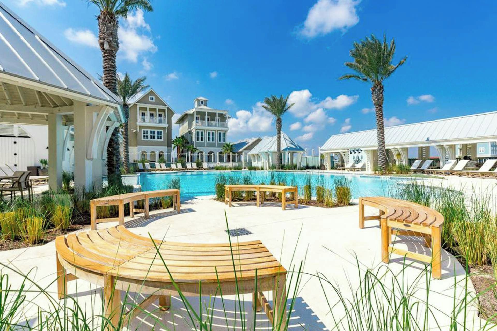 Un resort con piscina, sillas de descanso y palmeras.