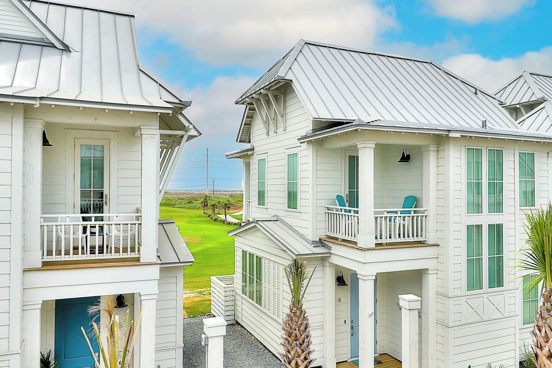 Une rangée de bâtiments blancs dotés de balcons, une vue dégagée sur un terrain de golf et une porte bleue.