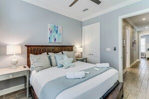 A well-lit bedroom with a large bed, bedside lamps, a decorative starfish pillow, and a painting on the wall. - Family Beach Retreat| Bunk Room | Resort Amenities (Port Aransas)