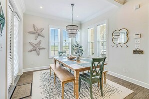Ein Essbereich mit Holztisch, Stühlen, einer Chandelierleuchte, Wanddekoration mit Seesternen und einem großen Spiegel.