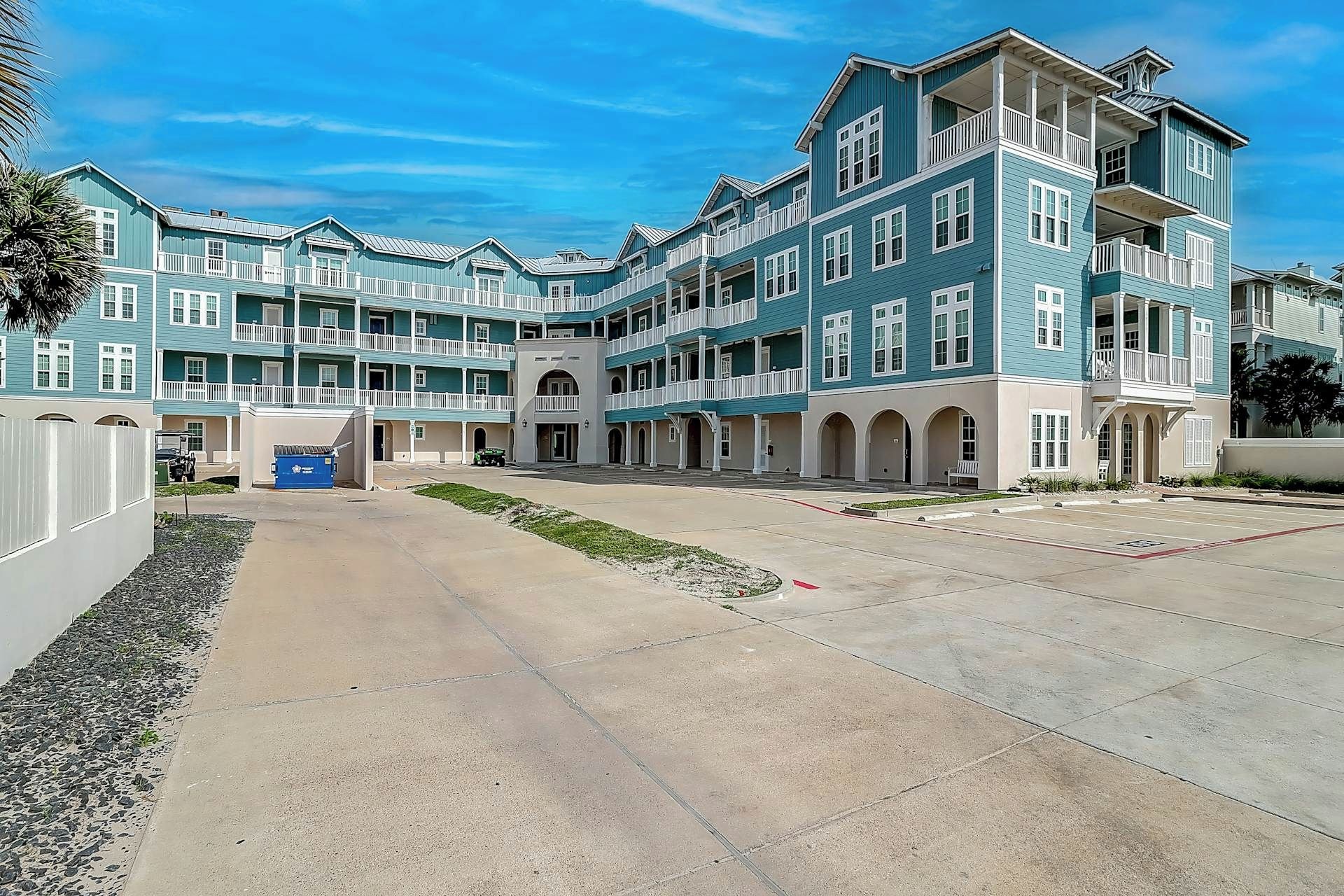A multi-story hotel with a central courtyard, balconies, and a parking area.