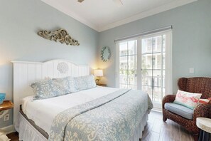 Ein Schlafzimmer mit einem großen Bett, einem Sessel, einem Fenster und einer Wanddekoration.