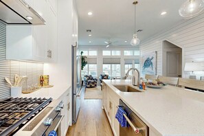 Una cocina moderna con una isla central, electrodomésticos de acero inoxidable y vistas al exterior.