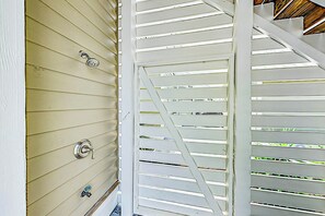 Eine weiße Tür mit einem Metallgriff und Schlüsselloch, neben einem weißen Fenster mit horizontalen Rollläden.