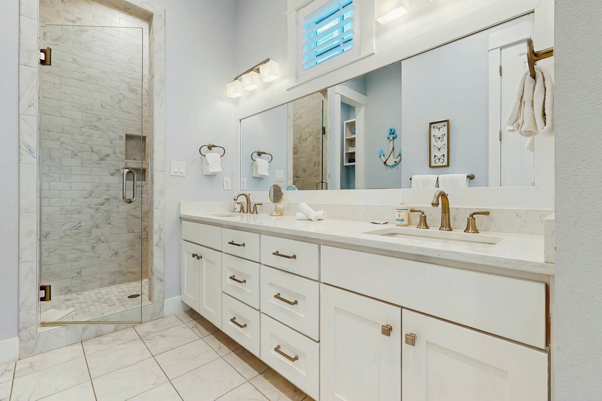 A modern bathroom with a large mirror, dual sinks, and a shower area.
