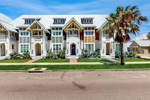 A multi-story residential building with a symmetrical facade, multiple balconies, and a central entrance. - Parrots Cove | Golf Views | Pet Friendly (Port Aransas)