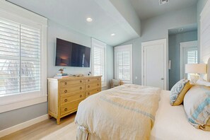 Quarto com cama, penteadeira e TV de tela plana presa na parede.