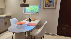 A dining area with a table, chairs, a wine bottle, and glasses. - Poolside One-Bedroom Retreat @ Villa Troyanda in Grace Bay (Providenciales)