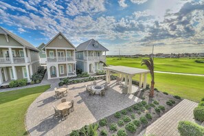 A multi-story house with a patio area featuring outdoor furniture and a fire pit. - Port Aransas Paradise | Golf Views| Resort Perks (Port Aransas)