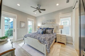 Un dormitorio con cama, mesitas de noche, ventilador de techo y ventana.